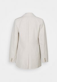 Blazer en lin beige avec un col à revers cranté, des manches longues et une fente unique à l'arrière. Présente quatre boutons décoratifs sur chaque poignet.