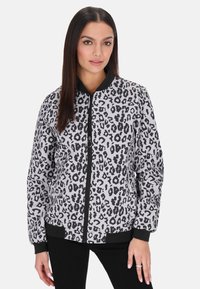 Bomber jacket s leopardím vzorem v bílé a černé barvě, s žebrovaným límcem, elastickými manžetami a předním zipovým zapínáním. Hladká textura tkaniny.