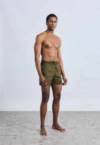 Meeste oliivrohelised ujumispüksid nöörvööga ja küljele trükitud logoga, valmistatud kerge ja kiiresti kuivava kangaga.