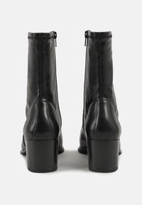 Bocanci negri din piele, cu fermoar, finisaj texturat, toc pătrat și un design elegant, ajustat care se estresează spre glezna.