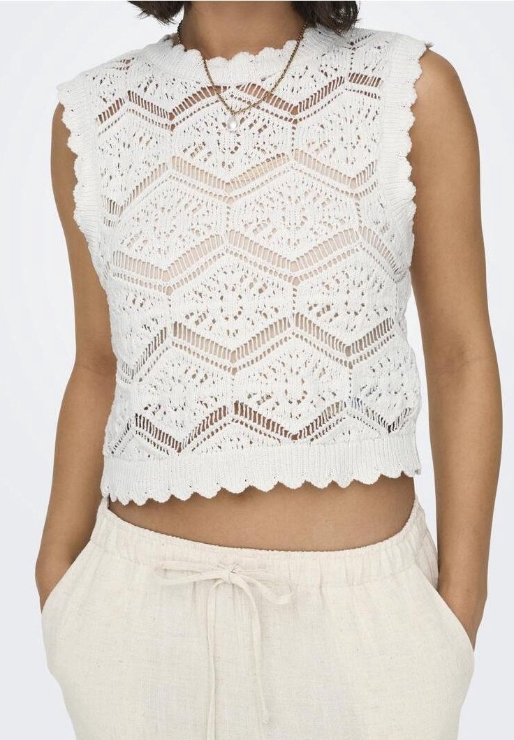 White knitted top with sleeveless design, featuring a hexagonal pattern and scalloped hem. Paired with light-colored linen pants.