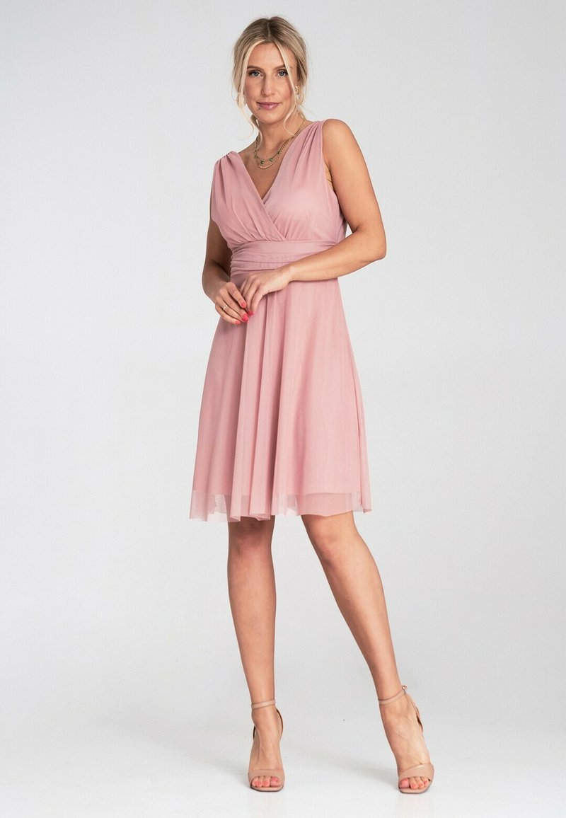 Blush-pink Kleid mit V-Ausschnitt, taillierter Taille und fließendem Rock. Hergestellt aus leichtem Stoff, mit strukturierten Akzenten und durchscheinendem Saum.