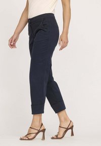 Pantalons bleu marine cropped avec une texture lisse, dotés d'un bouton à l'avant, de deux poches latérales et de bords retroussés.