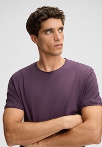 Paarse t-shirt met korte mouwen van zachte katoen. Heeft een ronde hals, subtiele stiksels en een relaxed fit. De textuur lijkt glad.