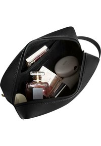 Black leather bag with a zip closure, interior showcasing various beauty products, including a glass perfume bottle and containers.