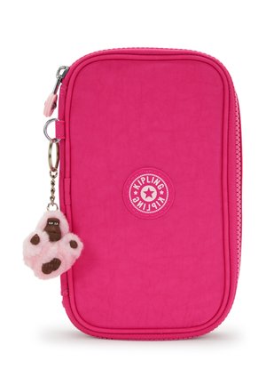 Bolso brillante de color rosa con cremallera, con el logo de Kipling y un pequeño llavero de mono de peluche colgado del tirador de la cremallera.