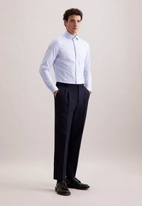 Koszula w paski w kolorze jasnoniebieskim i białym, z długimi rękawami, dopasowany krój. Do tego granatowe eleganckie spodnie i czarne skórzane buty.