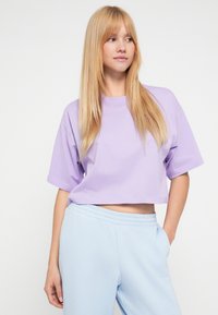 Ανοιχτό μωβ κοντομάνικη cropped μπλούζα, κατασκευασμένη από απαλό ύφασμα. Συνδυάζεται με ανοιχτό μπλε παντελόνι jogging με ελαστική μέση.