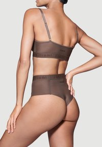 Braun nahtloses Bralette und hochgeschnittenes Unterwäsche-Set mit Logo-Band, verstellbaren Trägern und weicher Textur, das eine enge Passform zeigt.
