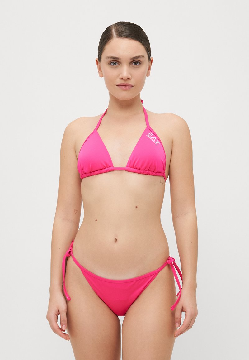 Rožinė trikampė bikini maudymosi kostiumėlis su plonomis petnešėlėmis ir surišamais šonais. Pagamintas iš minkštos, lygios medžiagos. Papuoštas subtiliu logotipu. 