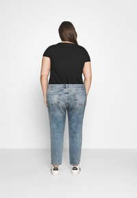 Black short-sleeve top paired with light blue faded jeans. The jeans feature back pockets. White sneakers with black accents complete the outfit.