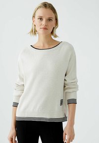 Hellbeige Pullover mit weitem Ausschnitt, gerippten Bündchen und schwarzen Streifenakzenten am Saum und Kragen. Weicher, strukturierten Strickstoff.