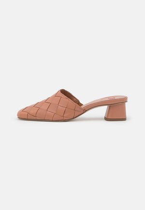 Mules de cuero trenzado en un suave color melocotón con punta afilada y tacón bloque. Textura lisa y diseño minimalista.