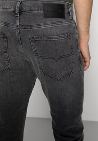 Vaqueros de mezclilla de color gris oscuro con un diseño de ajuste ceñido. Incluyen una etiqueta de cuero negro en la cintura y los cl�ásicos bolsillos traseros.