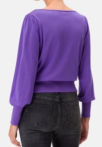 Pull violet court avec des manches bouffantes et des poignets côtelés. Fait en matériau doux, présentant un design simple et une encolure large.