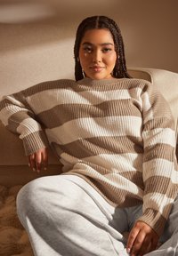 Randig tröja i ribbat material, med växelvisa bruna och krämfärgade ränder. Avslappnad passform med rundad halsringning och förlängda ärmar.