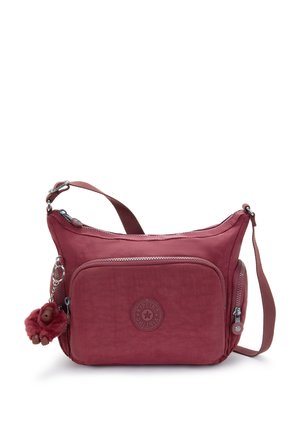Compact maroon crossbody bag with front and side zip pockets, adjustable strap, and a small plush monkey keychain attached.