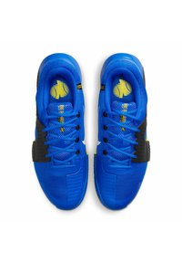 Ein Paar blaue Sportschuhe mit schwarzen Akzenten und gelben Logos, von oben auf einem weißen Hintergrund betrachtet.