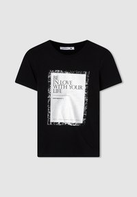 T-shirt in cotone nero con una grafica rettangolare bianca recante il testo "BE IN LOVE WITH YOUR LIFE" e un bordo consumato. Maniche corte, collo rotondo.
