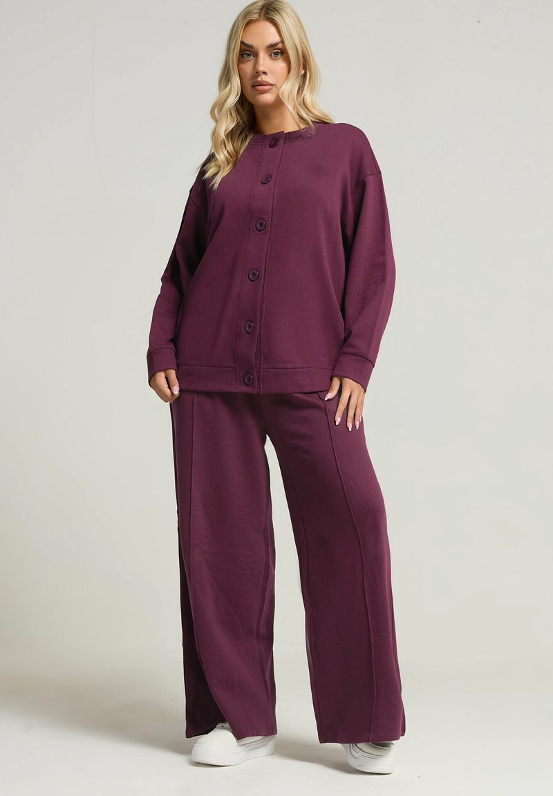 Burgundy lounge-set med en knapframsydd topp med långa ärmar och vida byxor. Mjuk tyg med minimal textur.