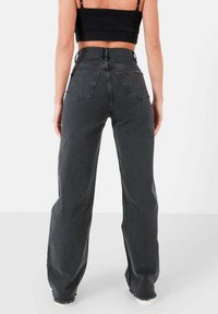 Hoge taille, wijde pijpen jeans in donkergrijs denim. Verweerde zoomdetails met twee achterzakken en een relaxte pasvorm. Katoenmix materiaal.