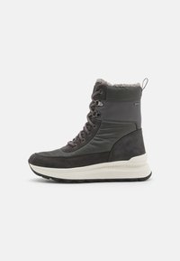 Botas altas en negro y gris que presentan una mezcla de cuero liso y ante, con forro de piel en la parte superior y una suela blanca acolchada.