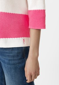 Gebreid sweatshirt met afwisselend roze en witte strepen, driekwart mouwen en geribbelde textuur. Gekocht met blauwe jeans, logo detail zichtbaar.