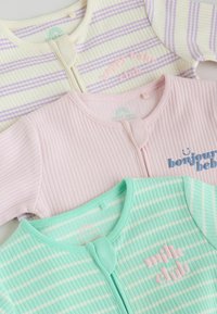 Trois bodies pour bébé côtelés en violet pastel, rose et vert menthe avec des fermetures à pression et des textes indiquant "happy baby club", "bonjour bébé" et "milk club".