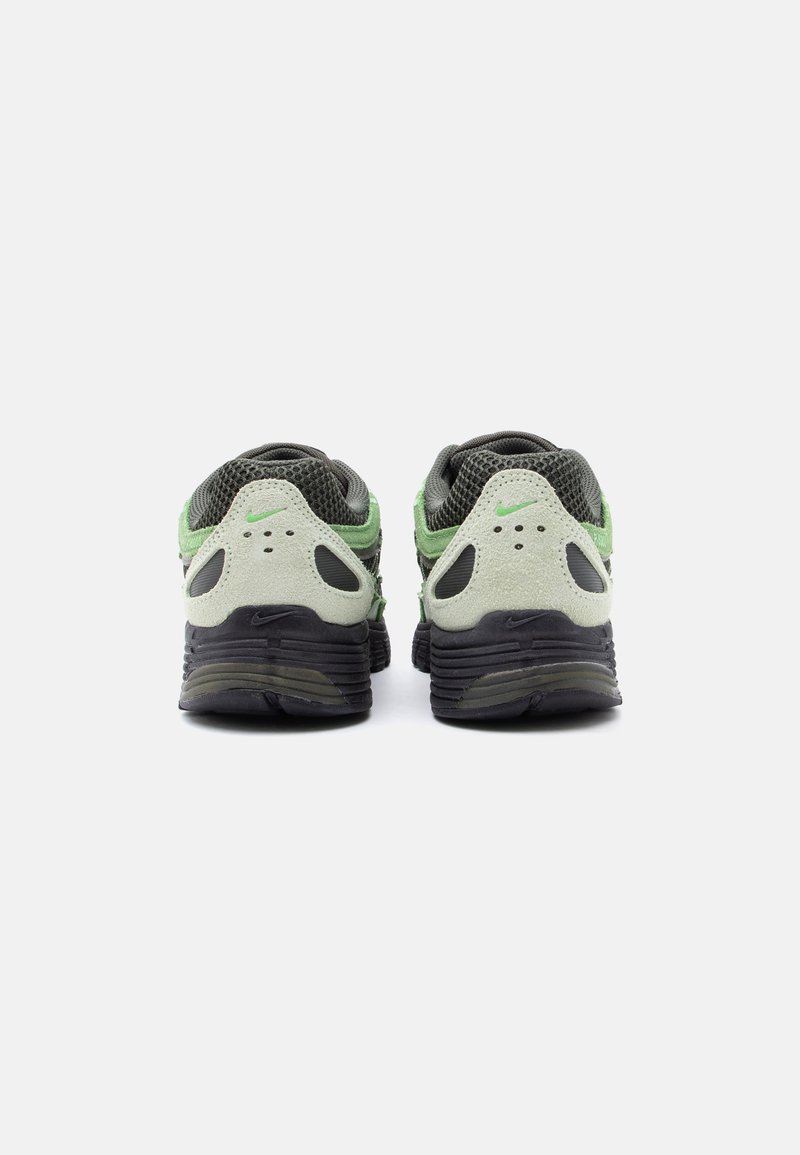 Paire de baskets Nike vertes, grises et noires vues de dos, en mesh et daim, avec logos Nike visibles.