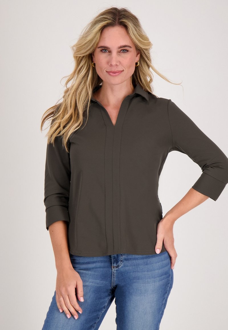 Donkergroene blouse met een kraag, voorzien van een V-hals en driekwartmouwen. Glad materiaal met subtiele stikseldetails.