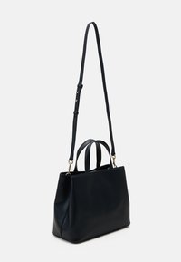 Schwarze Leder-Tote mit zwei oberen Griffen und einem verstellbaren Schultergurt. Glatte Textur, minimalistisches Design und Akzente in goldfarbener Hardware.