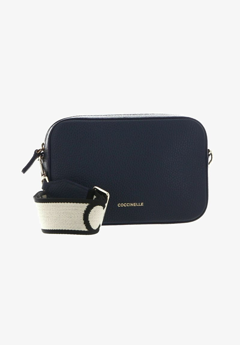 Marinblå läder crossbody-väska med pebblad textur, guld logotydelse och en kontrasterande rem med ett svart och vitt mönster.