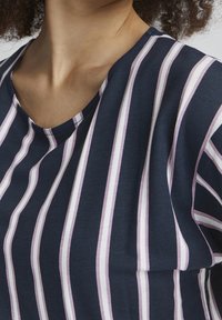 Navy blue top with vertical stripes in light pink and white. Features a rounded neckline and soft, textured fabric.