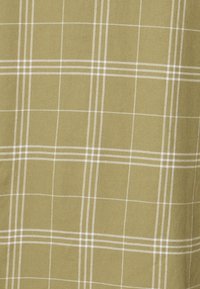 Olivgrönt tyg med ett rutmönster som har vita linjer. Texturen är slät, typisk för mjukt bomull eller fleece-material.