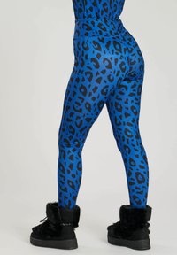 Blå leggings med ett svart leopardmönster, hög midja och en slät textur, tillsammans med svarta ankelstövlar med pälsfoder.