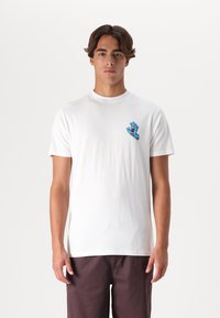 Hvid bomulds t-shirt med et blåt grafik af en hånd med et rødt accent i venstre brystområde. Korte ærmer, standard rund halsudskæring.