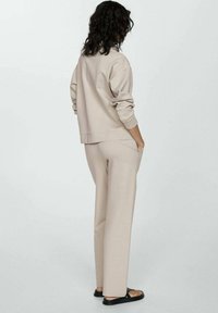 Felpa beige e pantaloni coordinati, entrambi realizzati in un tessuto morbido. La felpa ha una vestibilità comoda e polsini a costine, mentre i pantaloni presentano tasche laterali.
