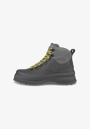 Bota de senderismo impermeable de color gris oscuro con suela gruesa y cordones de color amarillo brillante, mostrada de lado sobre un fondo blanco.