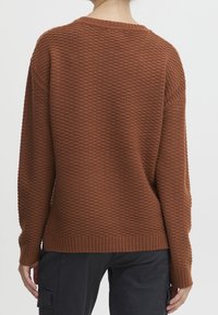 Suéter marrón de punto con un patrón texturizado, puños y dobladillo acanalados, y un ajuste relajado. Diseñado con un cuello redondo y mangas largas.