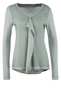 Maglietta a maniche lunghe con scollo a V in morbido tessuto verde pallido, con dettaglio drappeggiato nella parte anteriore, texture liscia e orlo arrotondato.