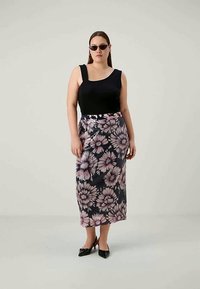 Top negru fără mânecă și fustă midi florală cu flori roz și negre, cu o croială ajustată, asortate cu pantofi cu toc înalt negri.