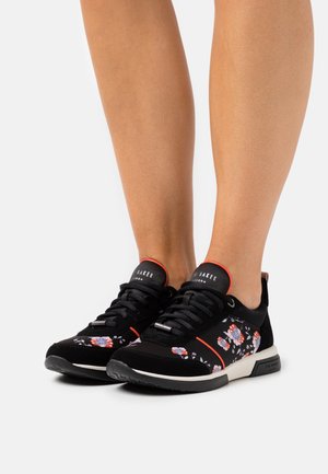 Baskets noires avec imprimé floral, tige en nubuck texturé, accents rouges contrastés, semelle en caoutchouc et lacets.