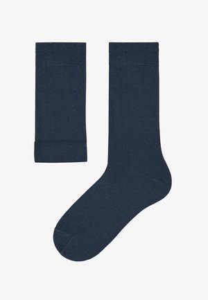 Marineblauwe sokken vervaardigd van een gladde, rekbare stof, met ribbels aan de bovenkant en een naadloos ontwerp bij de tenen. Twee sokken zij aan zij weergegeven.