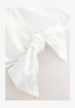 Hvid linnedstof med en knudedetalje, der har store, flydende ender og en let tekstureret overflade. Designet fremhæver blødhed og fald.