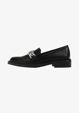 Mocassins en cuir noir avec une semelle plate, dotés d'une boucle métallique argentée et d'un détail de couture subtile le long du bord.