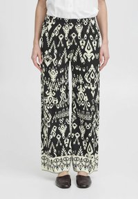 Pantalons larges en noir et blanc à motifs avec une taille élastique, présentant des formes et motifs complexes, et un détail de bord contrastant.