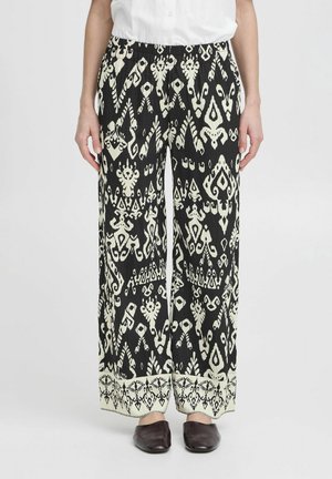 Black and white patterned wide-leg pants with an elastic waistband, featuring intricate shapes and motifs, and a contrasting hem detail.