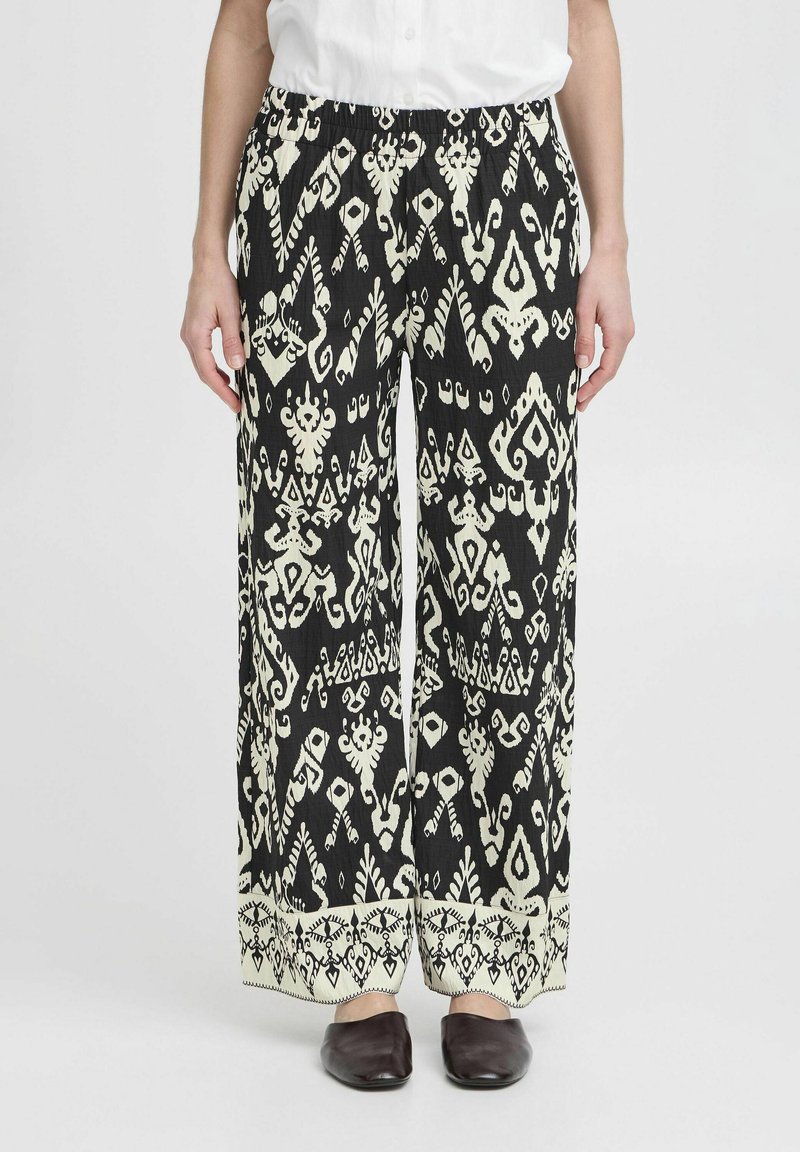 Pantalons larges en noir et blanc à motifs avec une taille élastique, présentant des formes et motifs complexes, et un détail de bord contrastant.