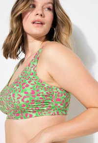 Groene panterprint bralette met roze accenten, met een ronde halslijn en gathering aan de zijkanten voor extra textuur. Gladde stof, getailleerd ontwerp.
