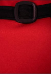 Gros plan sur une ceinture noire avec une boucle carrée sur un tissu rouge vif.